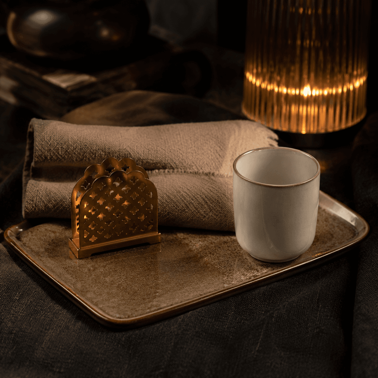A welcoming set for someone settling into a new place: ceramic tray, soft textile and a decorative holder.
